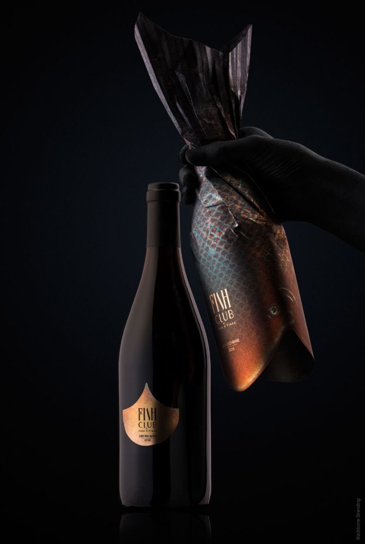 Black wine bottle with fish themed label and paper wrap making the bottle shaped like a fish