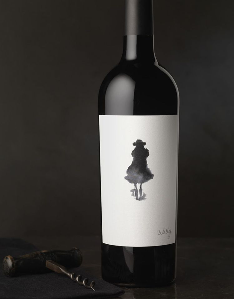 Black wine bottle with white label and ink blot graphic in the shape of a person
